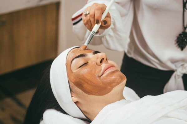 Woman receives a facial peel application while relaxing at a spa