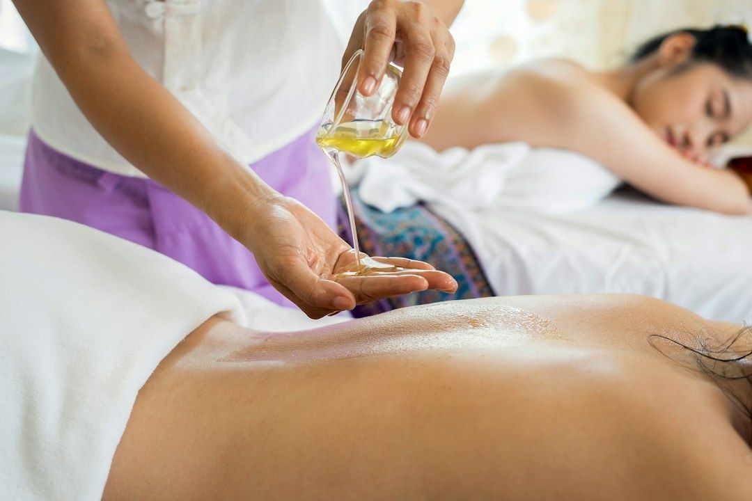 Practitioner applies massage oil to a client